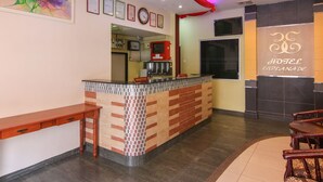 Zona de recepción de un hotel, con mostrador de recepción, un reloj, certificados enmarcados en la pared y un ventanal grande.