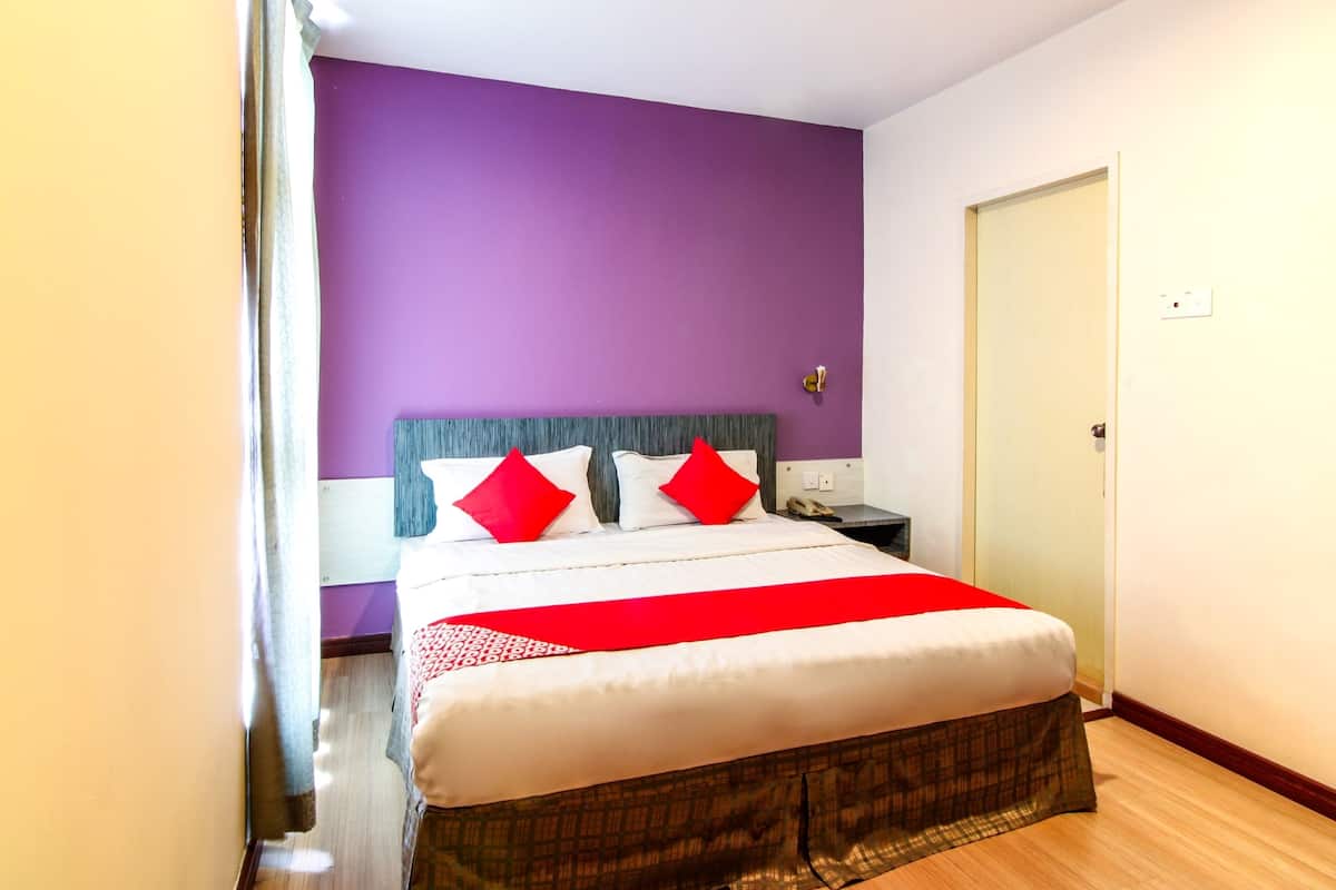 Una habitación de hotel con cama, mesita de noche, teléfono y puerta.