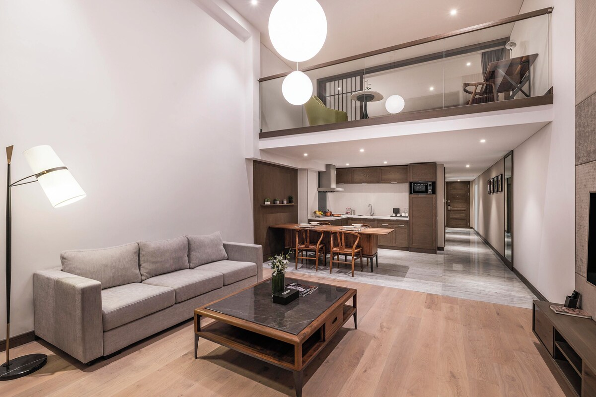 Ein modernes Wohnzimmer mit Sofa, Couchtisch und Essbereich. Im Hintergrund ist eine Küche zu sehen.