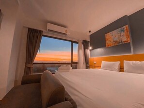 A hotel room with a large bed, a headboard, a painting on the wall, and a window with curtains. - Nornchill Khaoyai (Pak Chong)