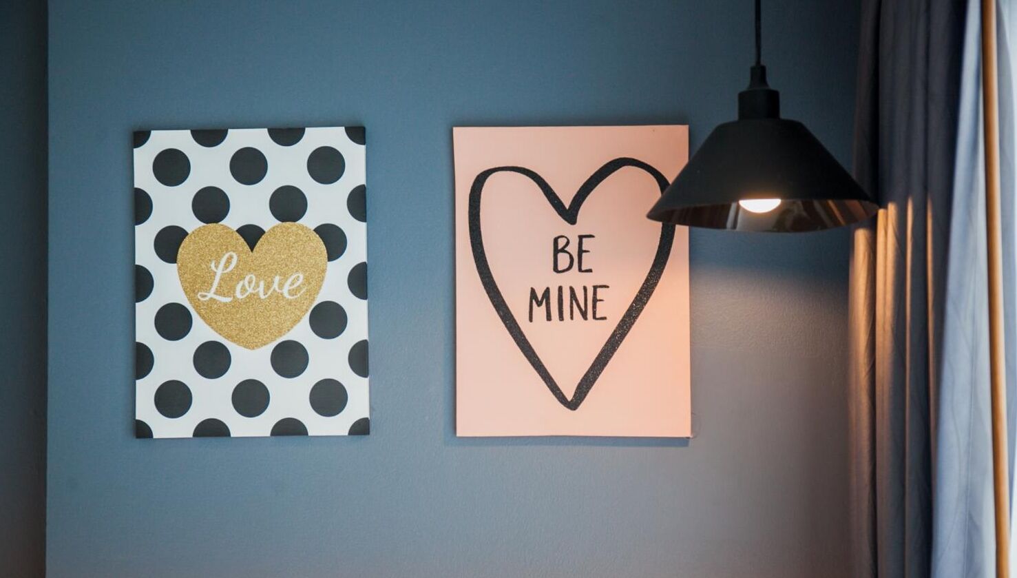 Dos adornos de pared: uno con estampado de lunares y un corazón dorado con la palabra "Love", y otro con forma de corazón y las palabras "BE MINE".