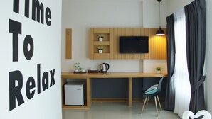 Eine moderne Küche mit Einbaukühlschrank, Mikrowelle und Kaffeemaschine. Ein Flachbildfernseher ist an der Wand angebracht und es gibt ein kleines Regal mit Pflanzen.