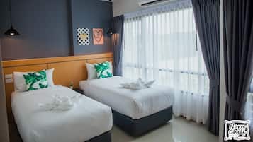 Habitación de hotel con dos camas, cabecera de madera, un ventanal grande con cortinas y un equipo de aire acondicionado.