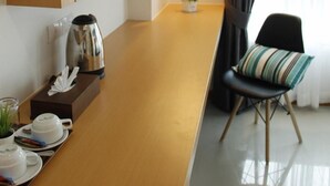Eine moderne Küche mit Holzschränken, einer Kaffeemaschine und einem Essbereich mit Stuhl und Tisch.