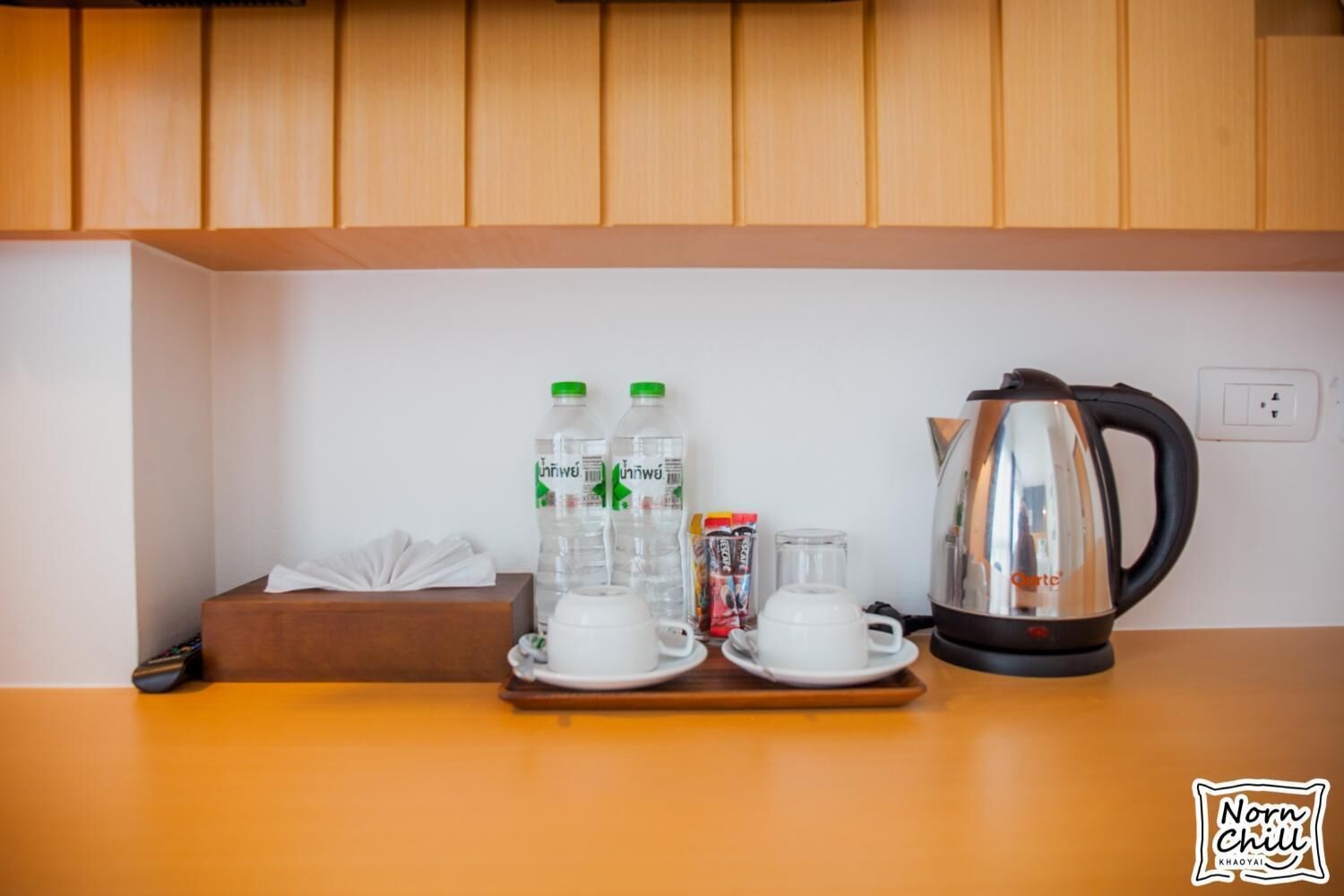 A kitchen counter with a coffee maker, two water bottles, a box of tissues, and a cup of coffee.
