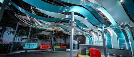 A modern indoor space with curved ceiling structures, seating areas, and a reception desk.