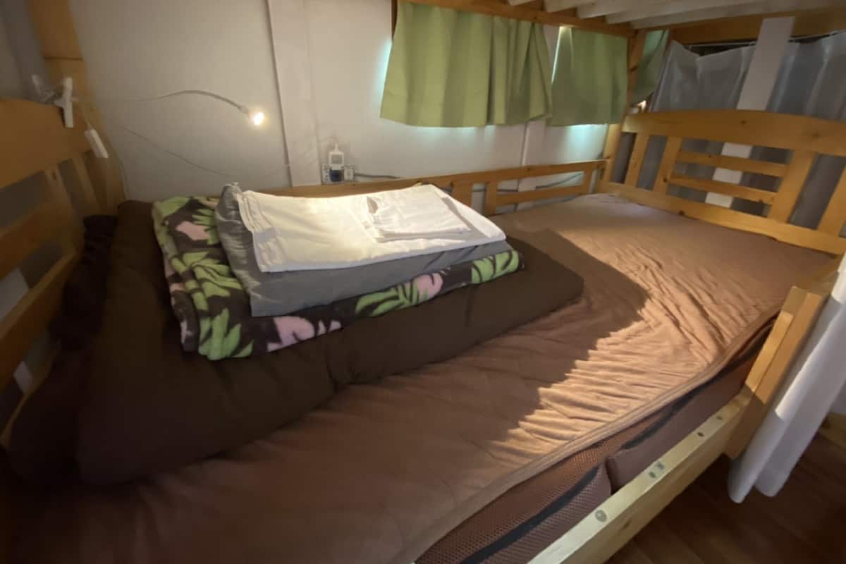 A bunk bed with a mattress, pillows, and folded clothes.