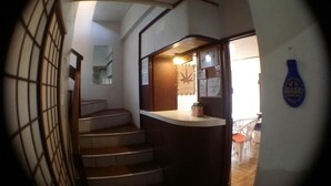 A staircase leading to a landing with a counter and a door. - Guesthouse Base Okinawa - Hostel (Naha)