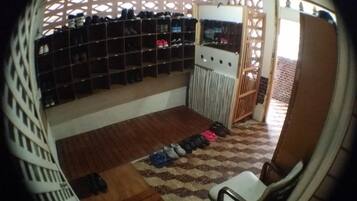 A room with a shoe rack, a chair, and a patterned floor.