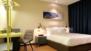 Une chambre d’hôtel comprenant un lit, un bureau avec une chaise, une table de chevet et une œuvre d’art accrochée au mur.