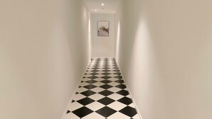 Un couloir étroit avec un sol à carreaux noirs et blancs et des murs blancs.