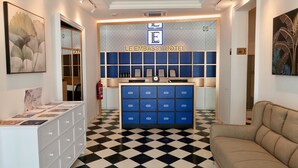 Un hall d’entrée avec un sol à carreaux, un comptoir de réception doté de tiroirs bleus et une enseigne indiquant « LE EMBASSY HOTEL ».