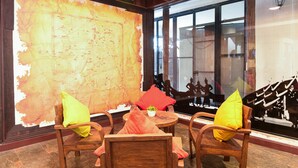 Un intérieur en bois, avec une grande carte accrochée au mur, des chaises en bois dotées de coussins et une vue par la fenêtre.