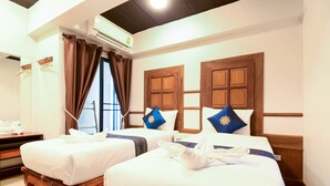 Une chambre d’hôtel avec deux lits, des têtes de lit en bois et une grande fenêtre avec des rideaux.