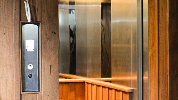 L’intérieur d’un ascenseur, avec un revêtement mural en bois et un panneau de commande métallique.