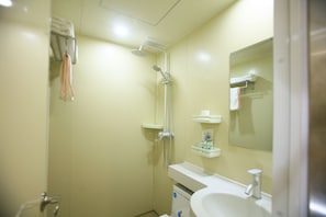 A small bathroom with a shower, a sink, and a mirror.