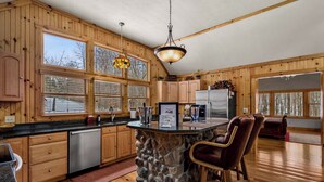 A spacious kitchen with wooden cabinets, a stone island, and a large window.