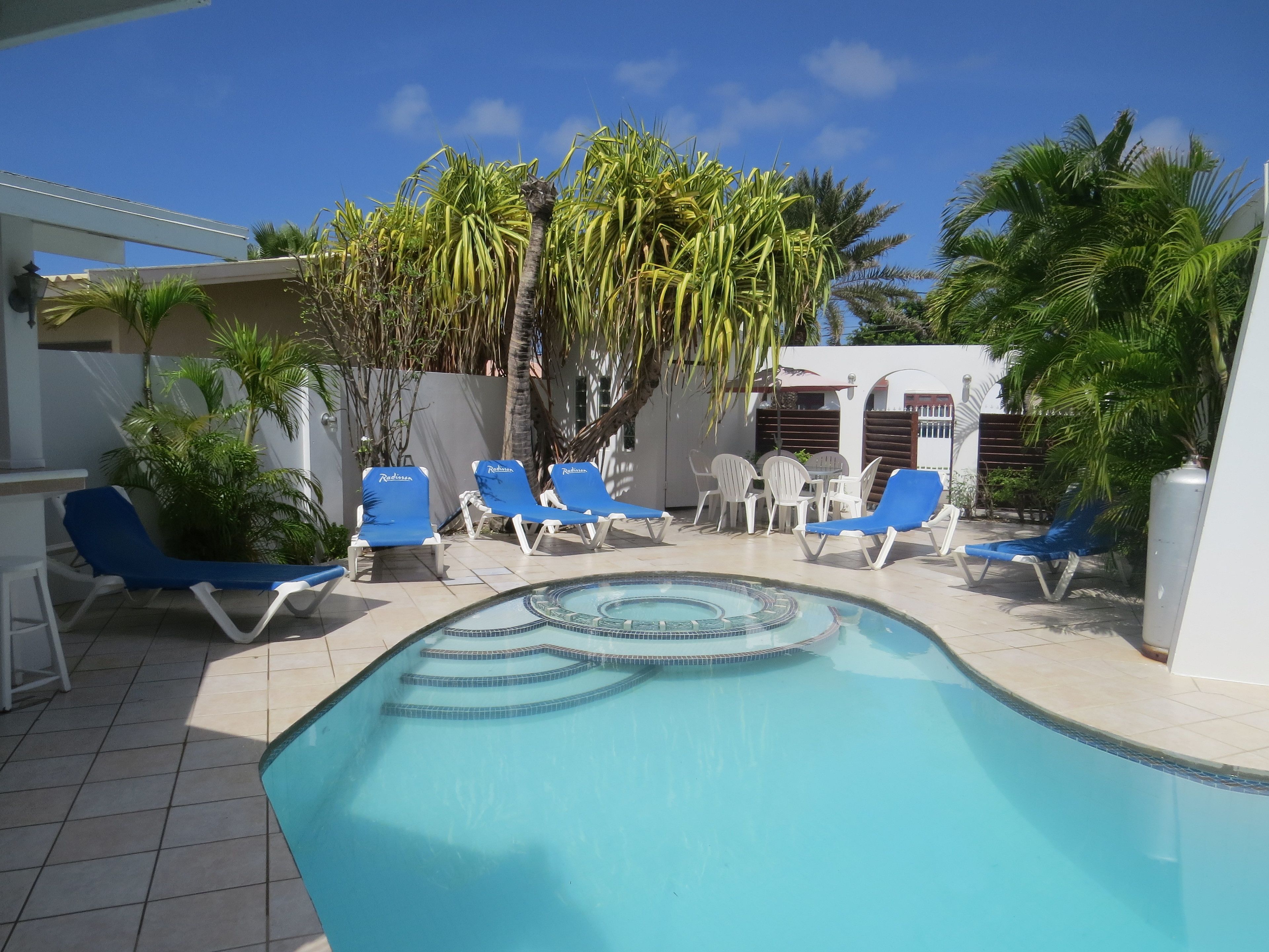 A pool area with blue lounge chairs and a tiled deck.