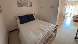 Quarto com cama, mesa de cabeceira e prateleira na parede.