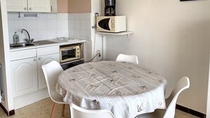 Uma cozinha compacta com armários brancos, micro-ondas, forno elétrico e pia.