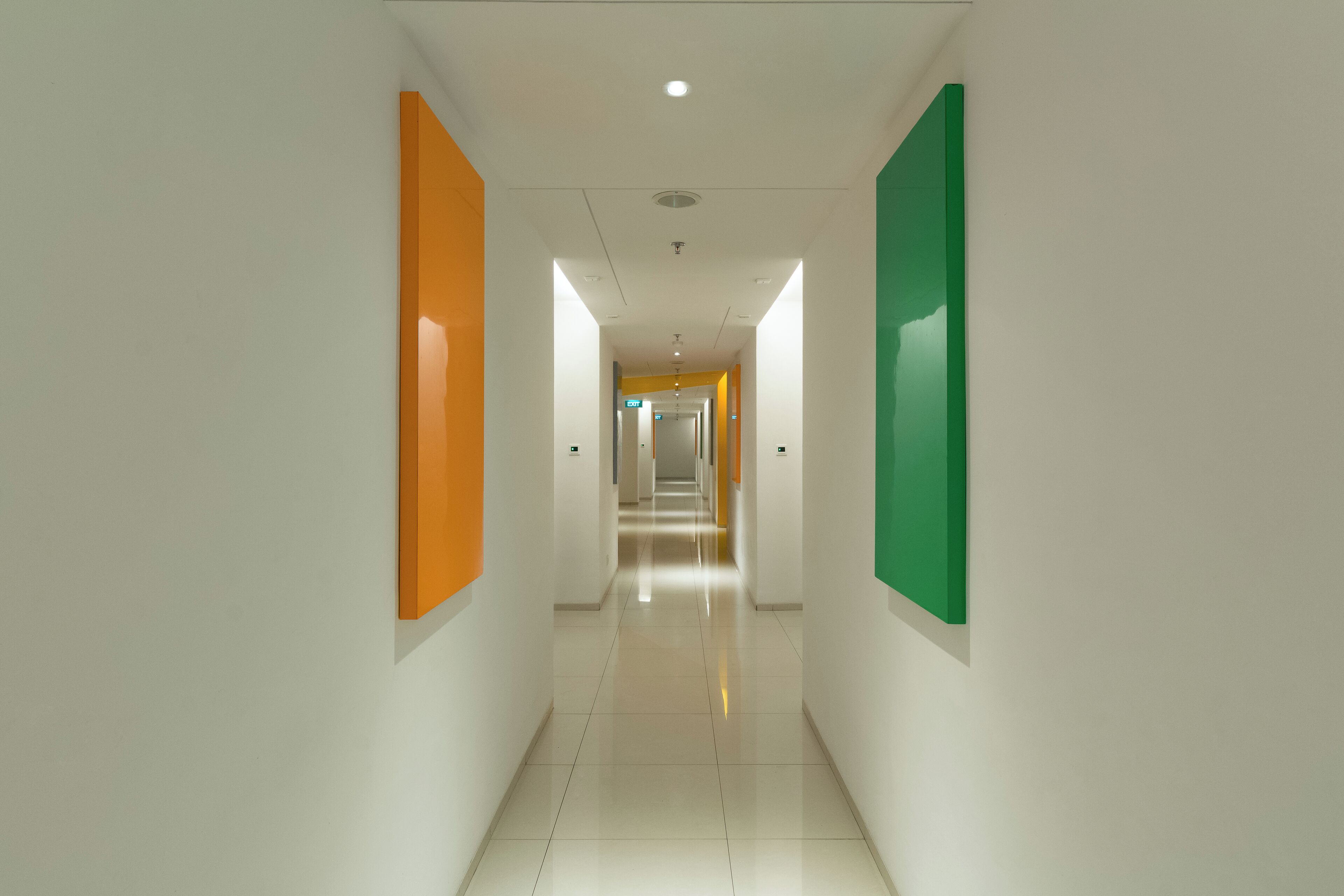 A modern, brightly lit hallway with white walls and colorful panels.