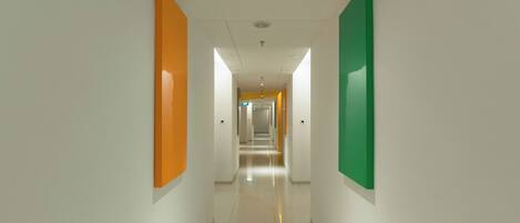A modern, brightly lit hallway with white walls and colorful panels.