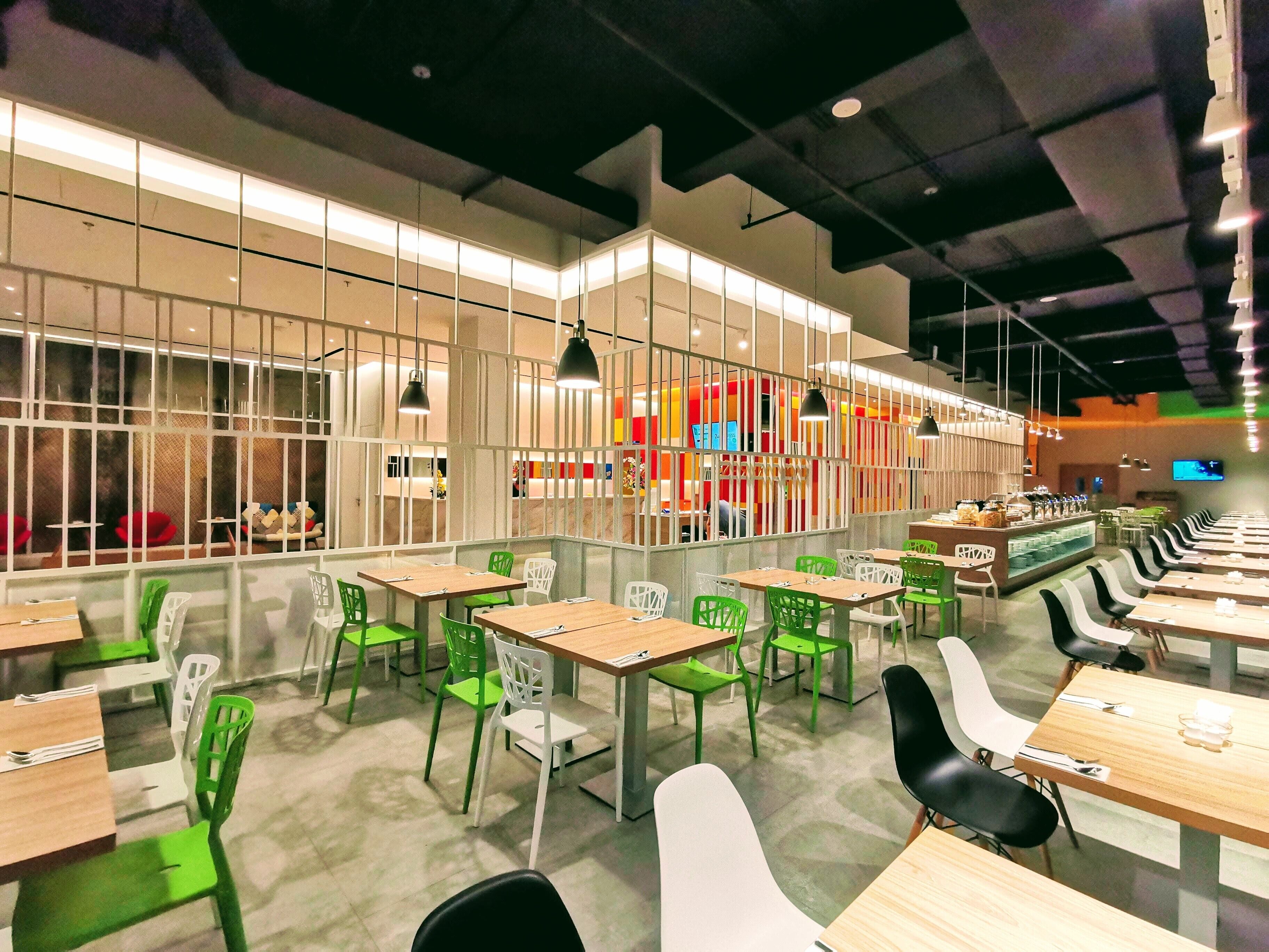A modern restaurant with multiple dining areas, including booths and tables.