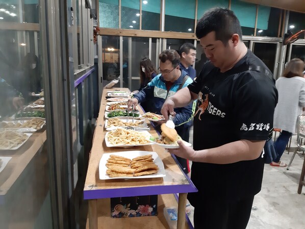 A buffet setup with various food items and a person serving food. - Erping Mountain Resort (Shuili)