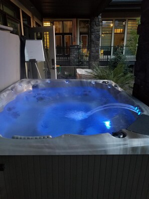 Ein Whirlpool mit Steinfassade und Blick auf ein Gebäude mit großen Fenstern und einem Balkon.