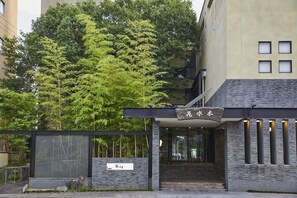 Un edificio moderno con un letrero que dice "Flower Water" y un árbol grande en la fachada.
