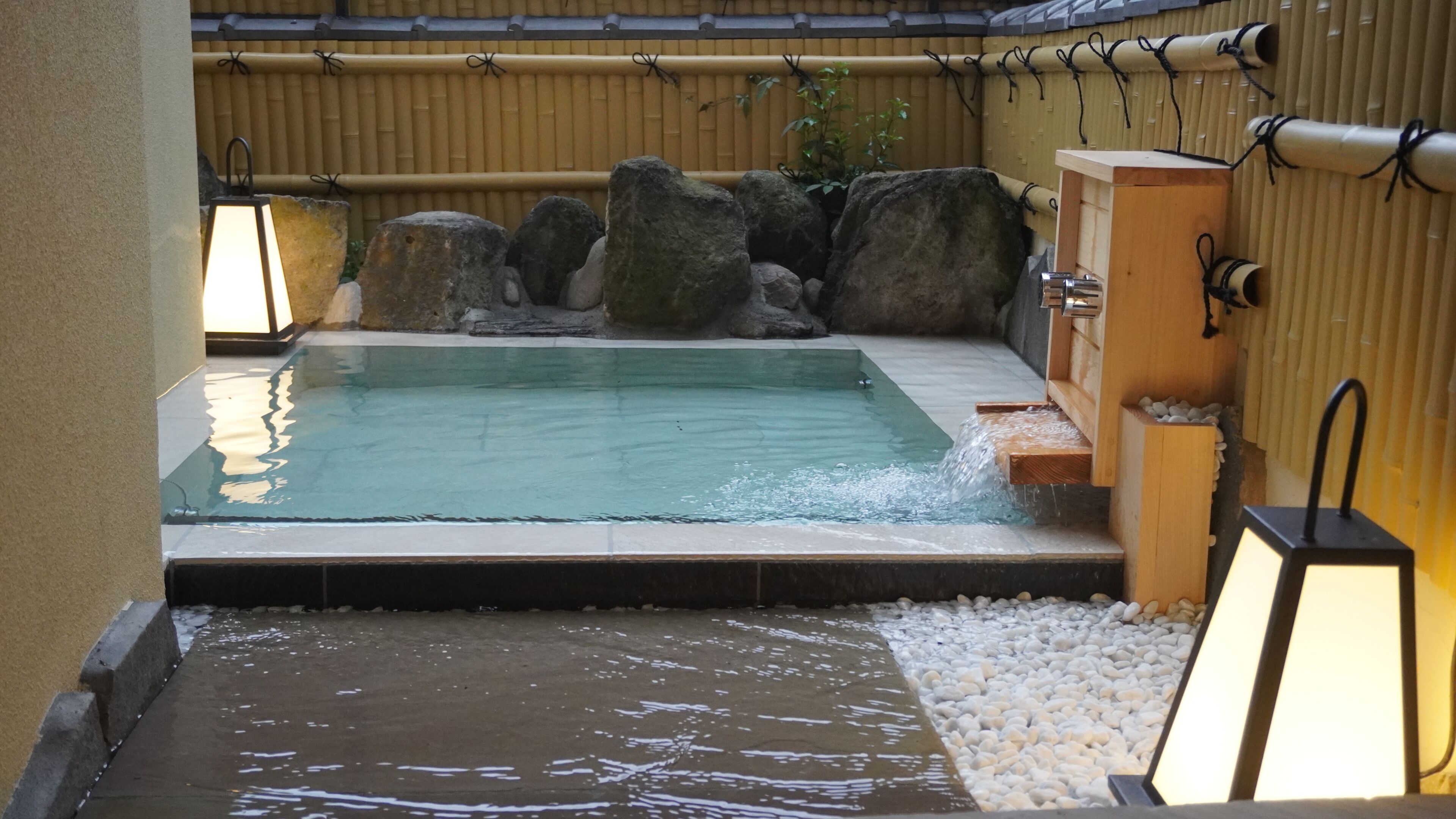 A hot spring area with a pool, rocks, and a wooden structure.