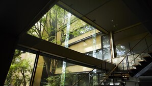 Un bâtiment moderne doté d’une façade en verre, d’un escalier et offrant une vue sur les arbres à l’extérieur.