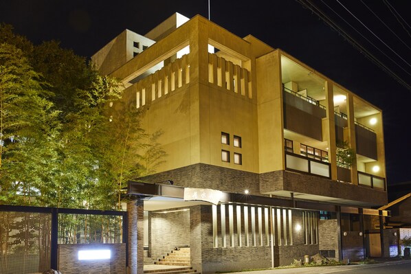 Un edificio moderno de dos pisos con techo plano, ventanas amplias y un área de entrada cubierta.