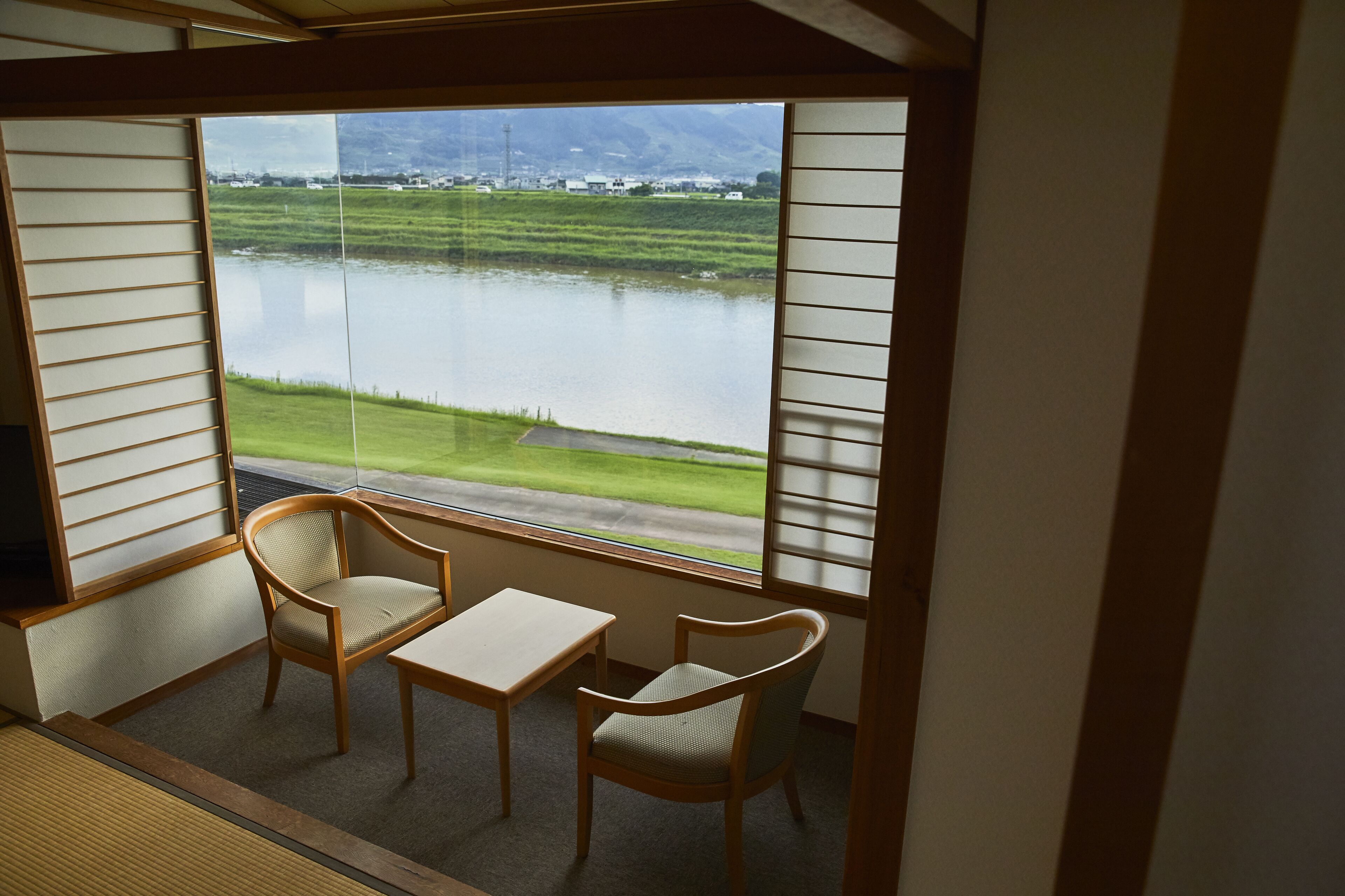 Una habitación con vista a un lago, dos sillas y una mesa pequeña.