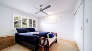 A bedroom with a bed, a wooden bench, a ceiling fan, and a window with blinds. - Best Location Welcoming Home (Buddina)