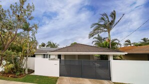 A modern house with a tiled roof, a gated driveway, and a well-maintained lawn. - Best Location Welcoming Home (Buddina)