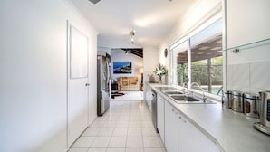A modern kitchen with a large window, a built-in oven, and a sink. - Best Location Welcoming Home (Buddina)