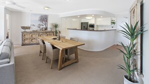 Una cocina moderna con armarios blancos, una mesa de comedor de madera y una isla integrada.