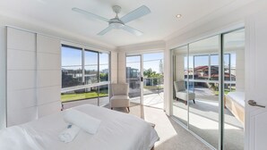 Una habitación de hotel moderna con una cama grande, un ventilador de techo y un balcón con vista a la ciudad.