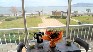A balcony with a table set for two, a vase of flowers, a black kettle, and two bowls. - Air-conditioned apartment near the Thermal Baths in Balaruc-les-Bains (Balaruc-les-Bains)