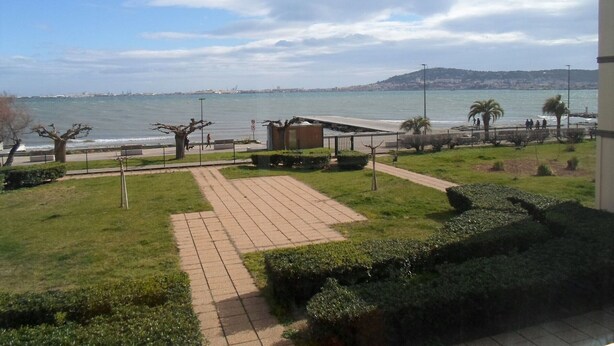 A coastal promenade with a paved walkway, benches, and palm trees. - Air-conditioned apartment near the Thermal Baths in Balaruc-les-Bains (Balaruc-les-Bains)