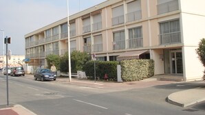 A multi-story building with balconies, a parking lot, and a street with cars. - Air-conditioned apartment near the Thermal Baths in Balaruc-les-Bains (Balaruc-les-Bains)
