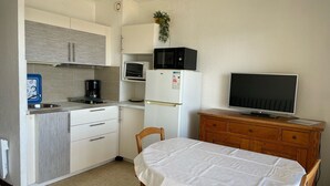 A compact kitchen with a microwave, refrigerator, and a small dining table with chairs. - Cozy apt facing the pond, 2 stars, pets allowed (Balaruc-les-Bains)