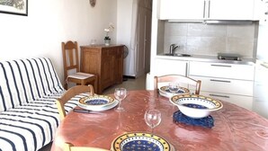 A dining area with a marble table set for four, surrounded by white cabinets and a kitchen area. - Cozy apt facing the pond, 2 stars, pets allowed (Balaruc-les-Bains)