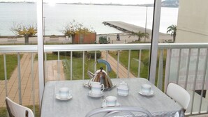A balcony with a table set for tea, overlooking a body of water and a distant shoreline. - Apartment 5 min from Thermes in Balaruc - Pets allowed (Balaruc-les-Bains)