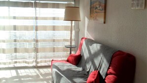 A room with a sofa, a lamp, and a window with curtains. - Apartment 5 min from Thermes in Balaruc - Pets allowed (Balaruc-les-Bains)