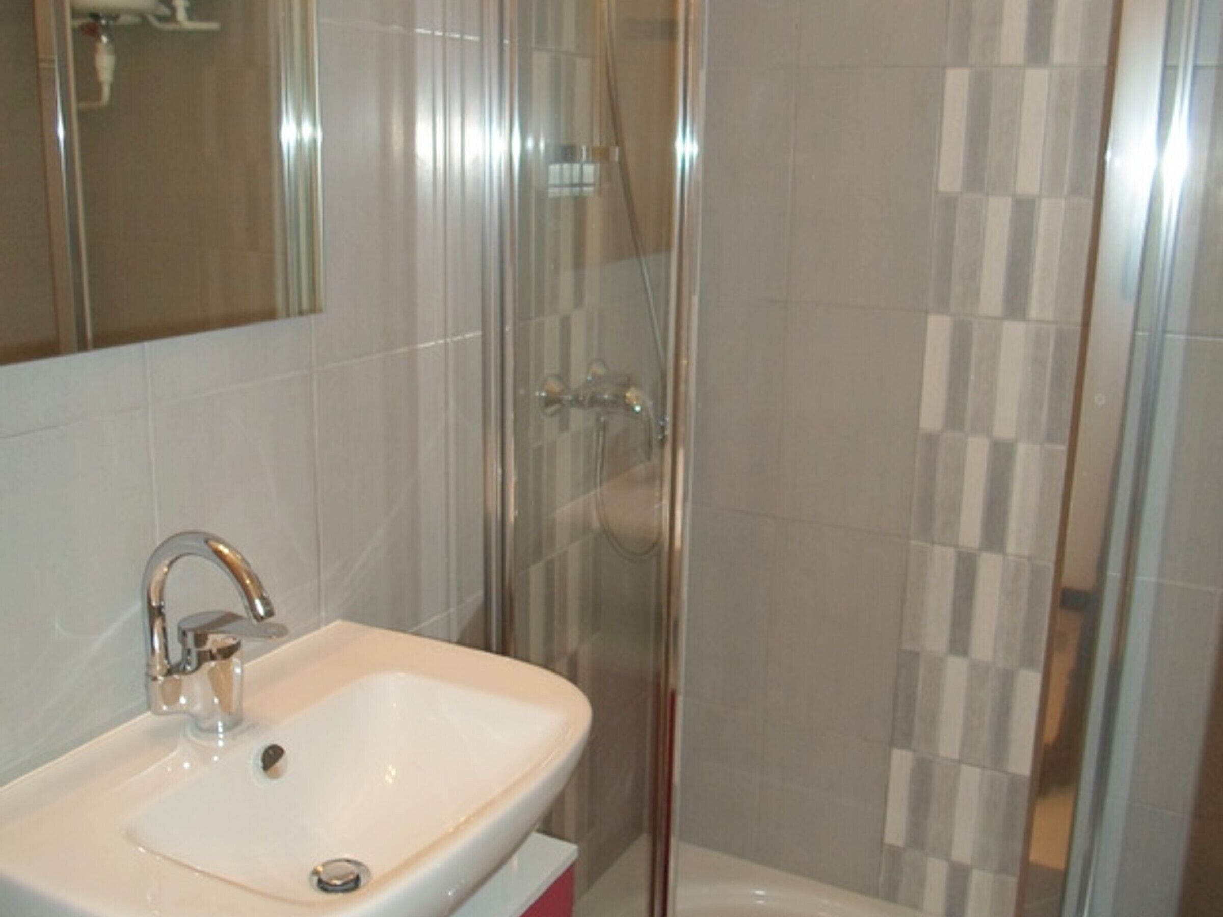 Une salle de bain équipée d’un lavabo, d’un miroir et d’une cabine de douche.