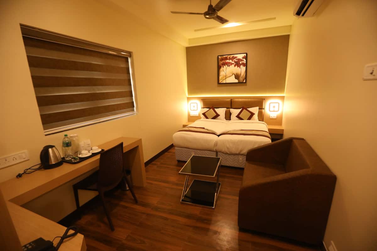 A compact hotel room with a bed, desk, chair, and a small table.
