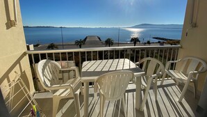 Un balcón con mesa y sillas, con vista a una masa de agua y una isla distante.