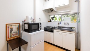 Une cuisine compacte équipée d’un four à micro-ondes, d’une cuisinière et d’un évier. On y trouve une petite table sur laquelle est posée une photo encadrée.